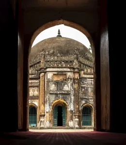 A view through an arched doorway revealing a historic Sheikh Mahmud Shah Masjid