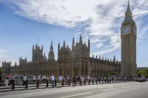 View of Big Ben and the Palace of Westminster with many tourists in the foreground under a partly cloudy sky