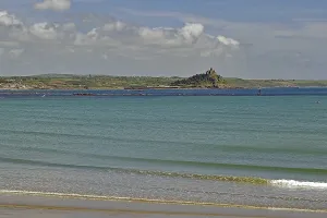View of a calm coastline with island and blue sea under a slightly cloudy sky