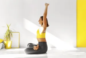 Side view of calm female in sportswear practicing yoga in Firefly pose while balancing on arms and looking away
