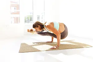 Side view of calm female in sportswear practicing yoga in Firefly pose while balancing on arms on mat and looking away