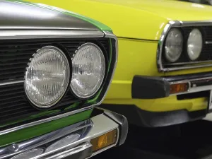 Front view of two classic cars in bright colours with striking headlights