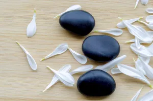 Top view of Close up view of fresh white flower next to stacked black stones natural balance with customizable space