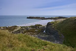 View of coast with rocks and beach under blue sky