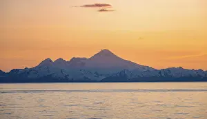 View of Cook Inlet on white mountain peaks of Mount Iliamna at sunset