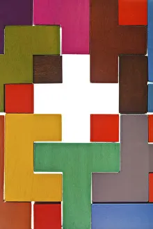 Top view of a cross-shaped hole in a multicolor wooden puzzle