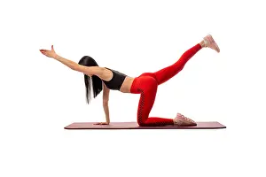 Side view of a flexible woman in sportswear standing on a mat and practising yoga on a white background