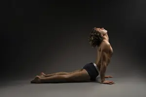 Side view of flexible young male in boxer briefs closing eyes