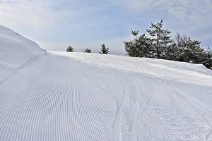 View on empty fresh-made downhill ski slope and mountains on a sunny day