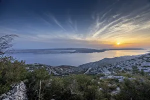 View of a hilly coastline and the island of Pag at sunset
