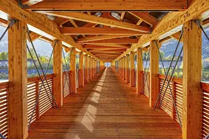 View along an illuminated wooden bridge with a view of the mountains and river