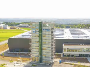 Front view of an industrial building with scaffolding and fields in the background
