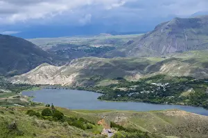 View of a lake nestled in mountainous landscape under cloudy sky