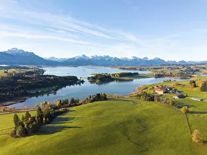 View of a lake surrounded by green hills and mountains under a clear blue sky