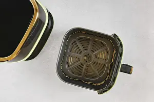 Top view of modern air fryer with empty basket lined with parchment paper