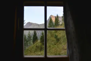 View of nature at sunset through a hut window to the summits of Weisser Spitze and Roter Spitze