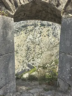 View through an old stone wall opening onto a barren rocky landscape