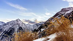 View from outskirts of Les deux Alpes village on mountain range with long yellow grass