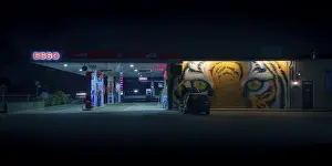 Category Historic EN Prints: View of a petrol station with a parked car in front of a painted facade at night