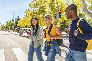 Side view photo with copy space of three multi-ethnic students walking along the city