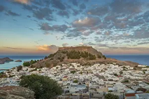 View of picturesque Lindos with the ancient Acropolis on a hill surrounded by the sea at sunset