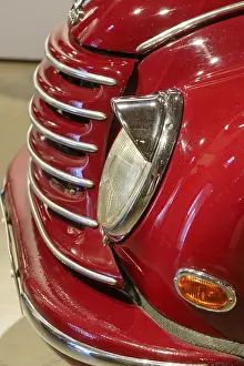 Front view of a red classic car with shiny chrome details and headlights