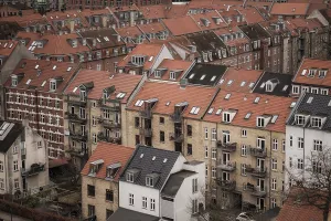 View of a residential area with red-tiled rooftops and brick buildings under a cloudy sky in Aarhus