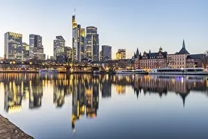 View over the river Main with a modern illuminated skyline in the background in the evening