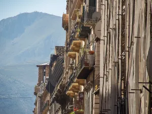 View of the sand-coloured buildings with balcony plants and a majestic mountain in the background
