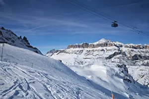 View of a ski resort piste with people skiing in Dolomites in Italy with cable car ski lift