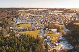 View of a small town in winter with snow-covered forests and fields