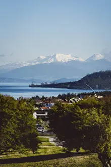 Framed Print : View of snow-capped mountains and a lake with a village in the foreground under a clear sky
