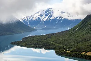 View of snowy mountains in spring and turquoise Kenai Lake with reflection