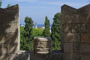 View from a stone wall with battlements of green trees and the distant sea under a blue sky