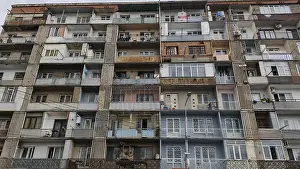 Front view of a symmetrical apartment block with many balconies and floors