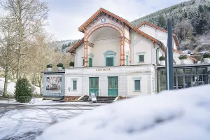 Front view of a theatre in the snow with wooded mountains in the background