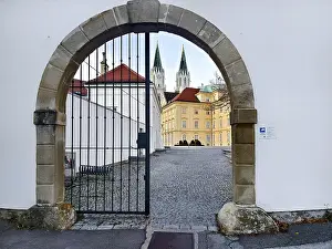 View through a Tor tor to a cobbled courtyard and church towers of a historic building
