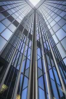 View upwards along an ultra-modern glass facade of a skyscraper with geometric shapes