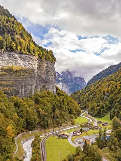 View of the valley with winding river and small settlement under wooded mountains