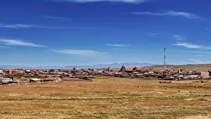 View of a village with church and antenna under wide sky surrounded by open fields