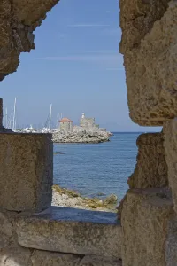 View through a wall of a medieval fort of Saint Nikolaos by the sea with sailing boats