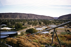 View of water reservoirs and building roofs, Alice Springs, Northern Territory, Australia in 1956 with a view of Heavitree Gap in the MacDonnell Ranges