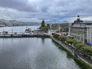 View of waterfront with boats and mountains in the background under cloudy sky