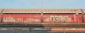 Category Historic EN Prints: View over a weathered crash barrier to a part of a goods wagon that has been painted with graffiti