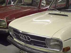 Front view of a white Audi classic car in a garage with a red car next to it
