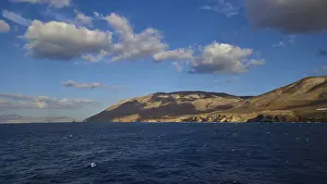 View of a wide seascape with mountains on the horizon under a blue sky