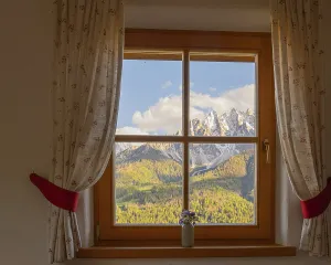 Framed Print : View through a window to the Dolomites in the foreground a small vase with meadow flowers on the windowsill Framed Print : View through a window to the Dolomites in the foreground a small vase with meadow flowers on the windowsill