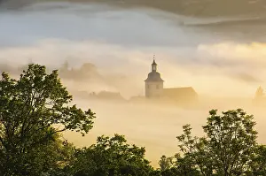 The village church of NiBmitz rises out of the morning mist