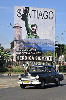 Vintage car driving in front of revolutionary propaganda poster