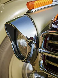 Detail of a vintage car with headlights and chrome-coloured finish